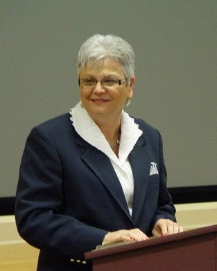 Dr. M. Paula Daoust speaking at a podium